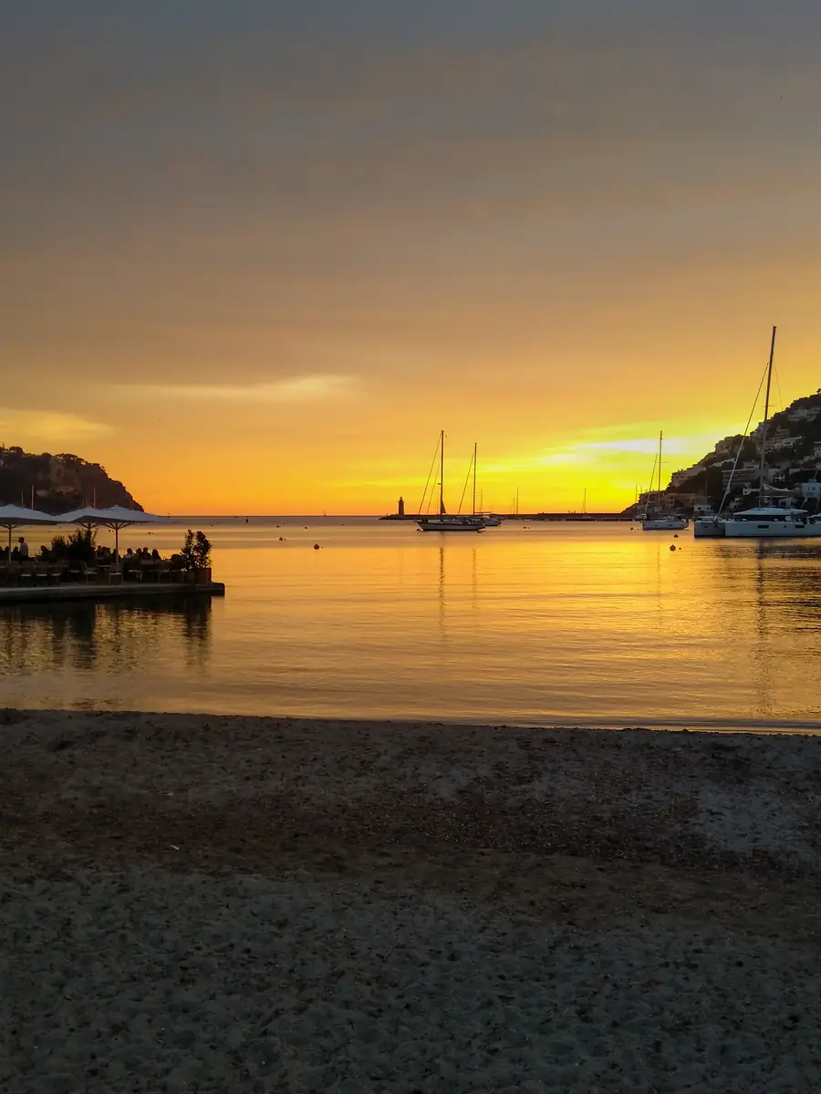 Sunset over Port d'Andratx: yachts at anchor, a lighthouse on the breakwater and the bay turning gold