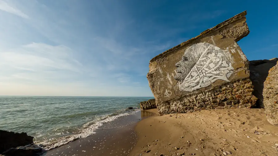 A collapsed fort block on the beach at Liepaja, a mural of an elderly woman in a lace shawl painted on its seaward wall
